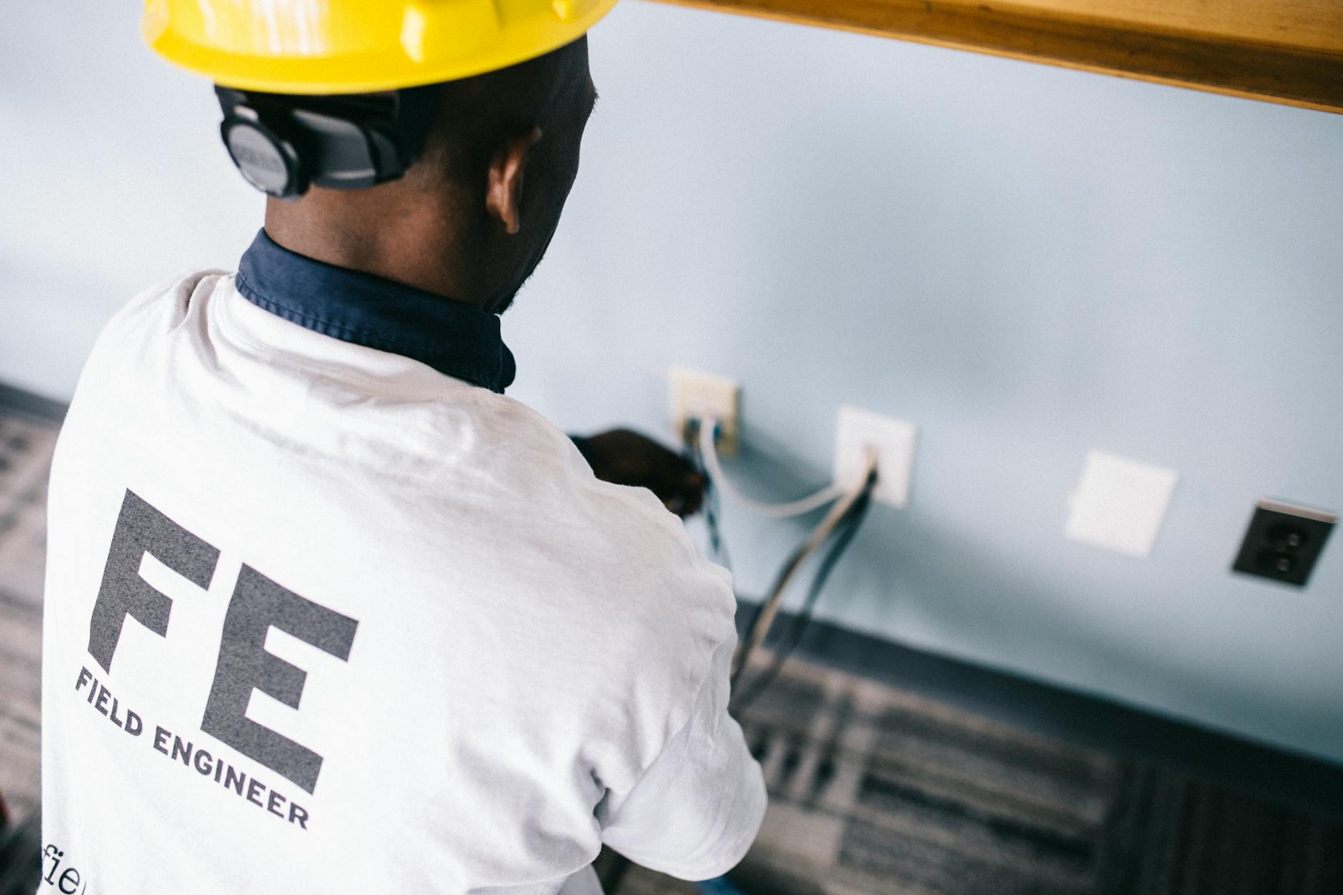 Elektryk w kasku mierzy napięcie w gniazdku ściennym