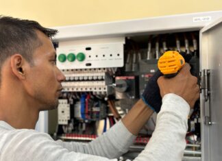Błędy przy montażu tablicy licznikowej i rozdzielnicy głównej: na co zwraca uwagę zakład energetyczny? Elektryk naprawiający sprzęt elektryczny wiertarką we wnętrzu