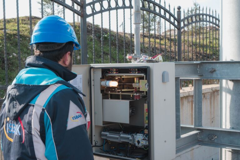Elektryk w kasku sprawdza zewnętrzną skrzynkę bezpiecznikową