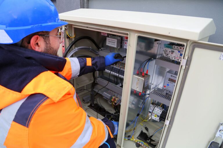 Elektryk w odzieży ochronnej przy zewnętrznej rozdzielnicy elektrycznej